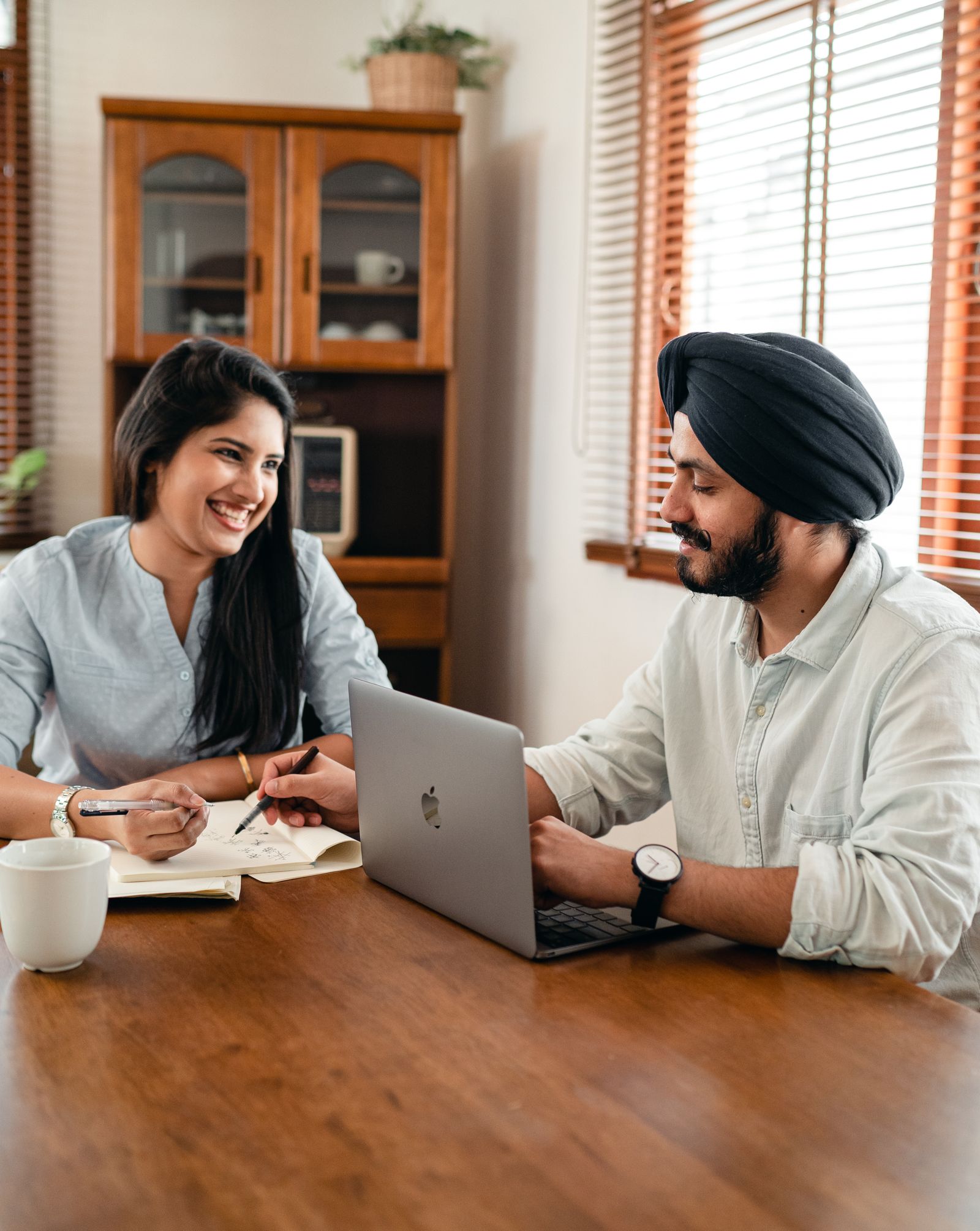 Two professionals at a desk celebrating with a high five, papers and a laptop in front of them