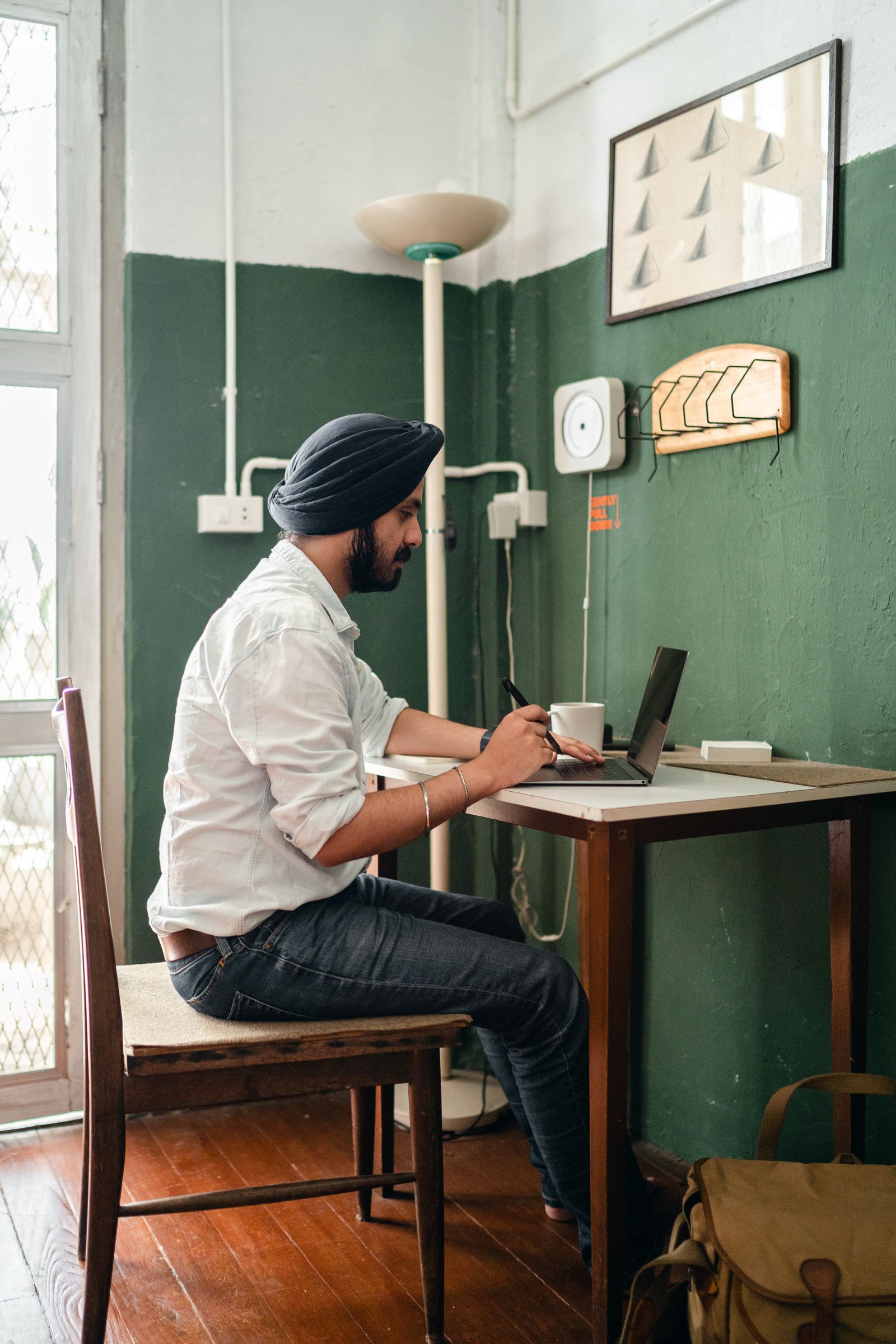 A founder with hands at his temples staring at a laptop, looking strained while working alone